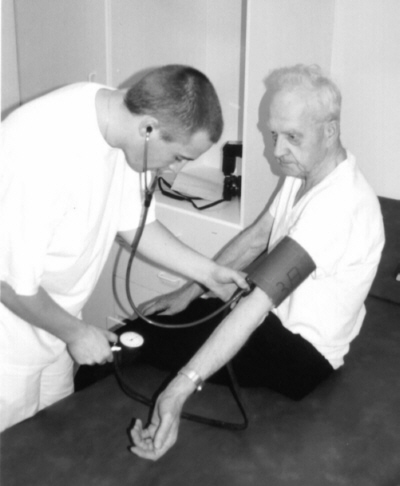 Das Bild zeigt einen Krankenpfleger bei der Untersuchung eines Patienten